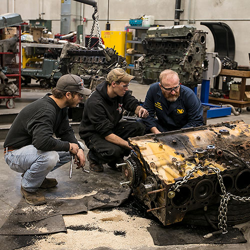 students and teacher looking a truck parts