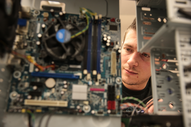 Close up photo of student looking at the components of a computer.