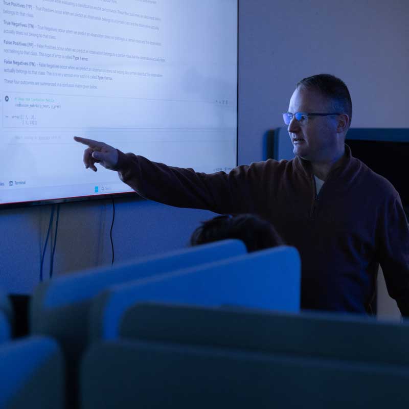 LCCC AI instructor talking to class and pointing at code on the screen