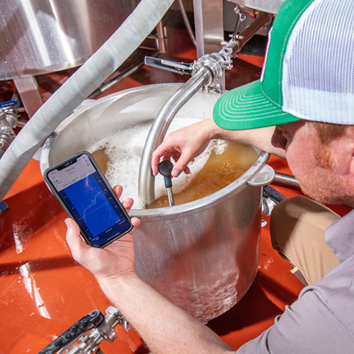 man brewing beer using equipment tools to measure