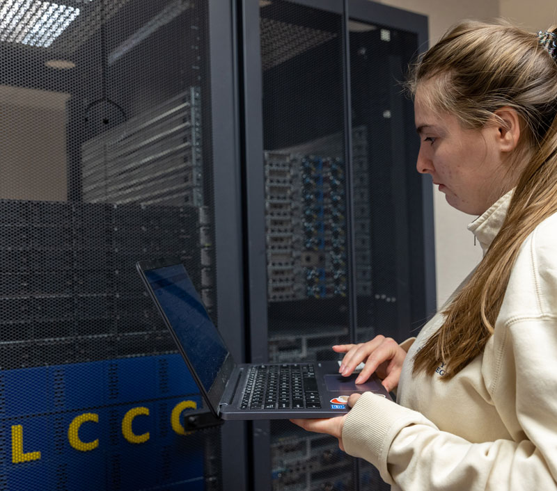 female student with laptop near servers