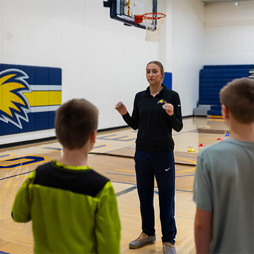 exercise science student teaching kids games in the basketball court