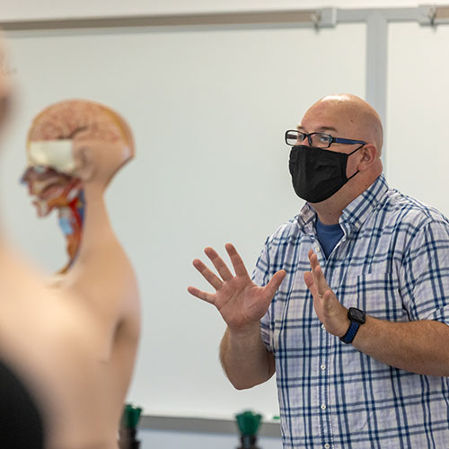 instructor talking to class with medical model of body