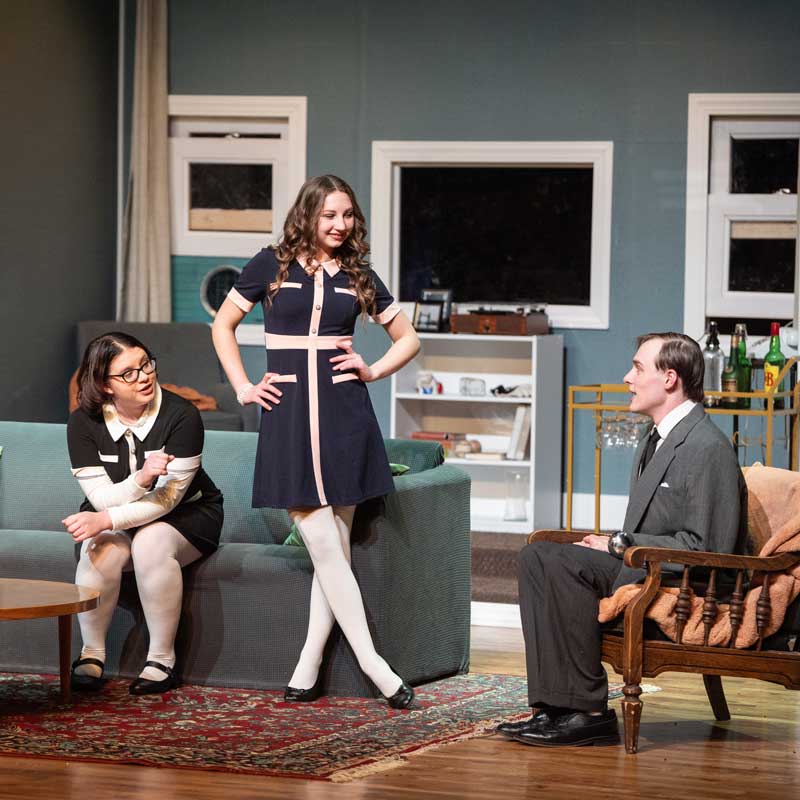 three actors on stage during a play in a 50s style living room set
