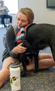 Student hugging therapy dog.