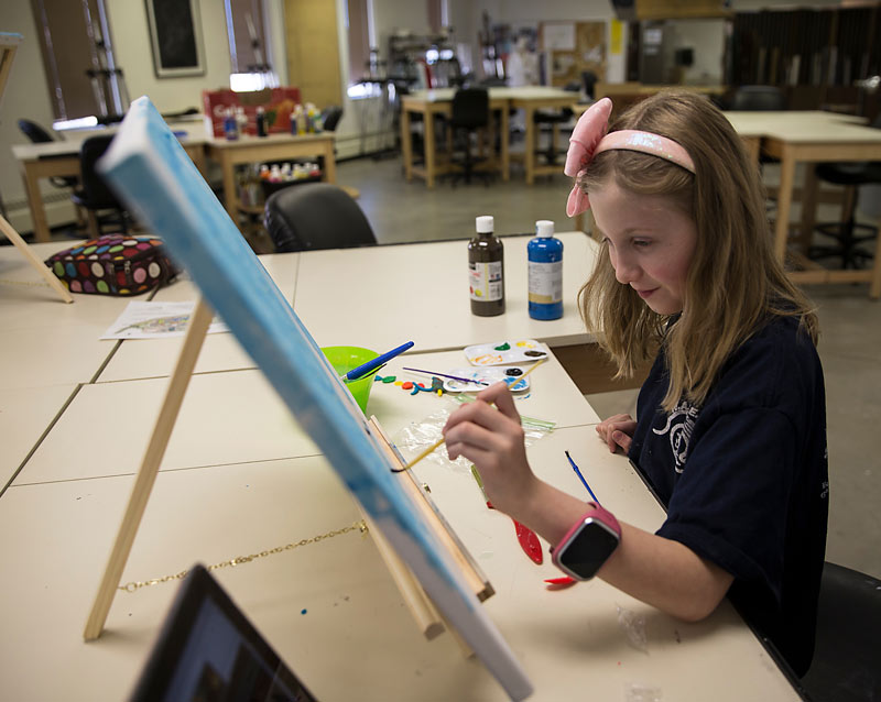 young girl painting in class