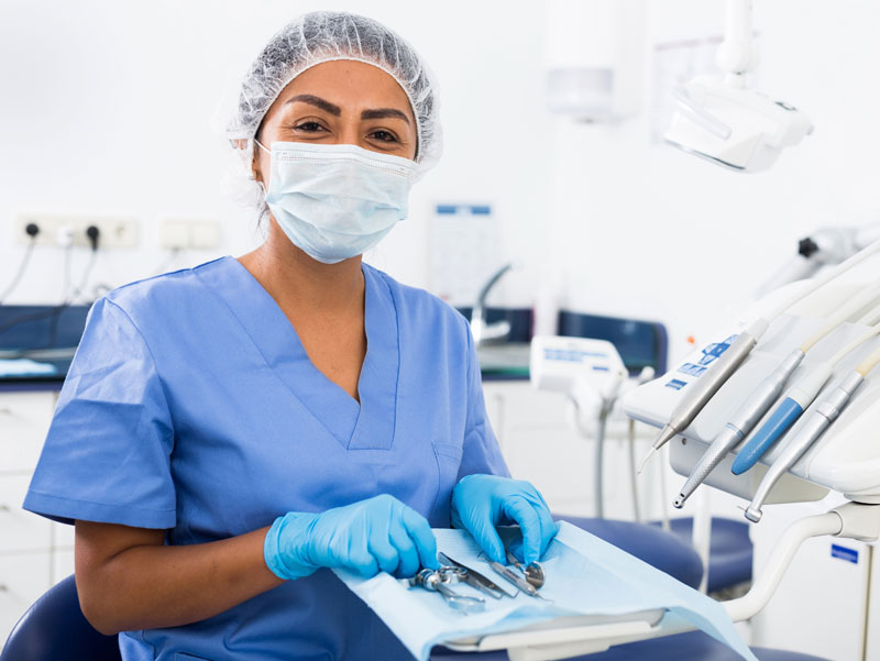 Photo of a dental assistant with mask, gloves and dental tools