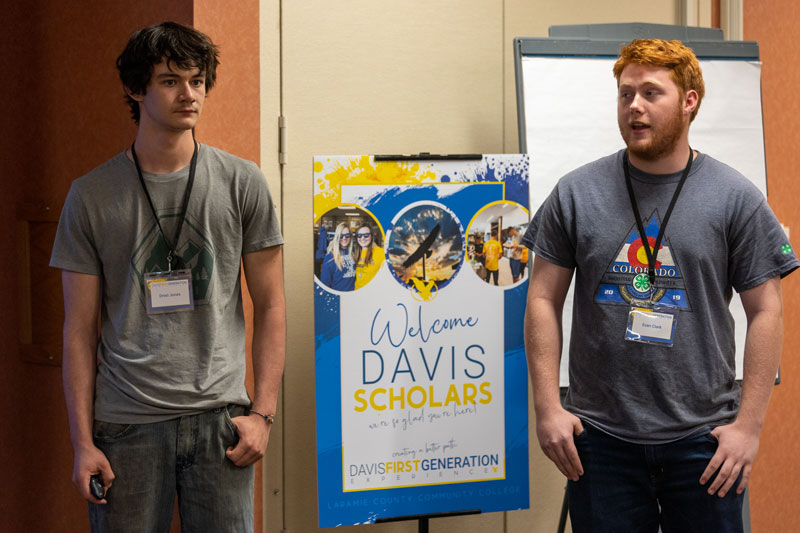 Photo of two students standing and talking near a Davis Scholar sign