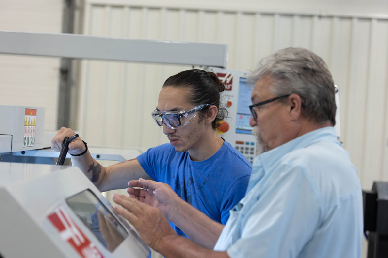 photo of a student and instructor working on a CNC machine